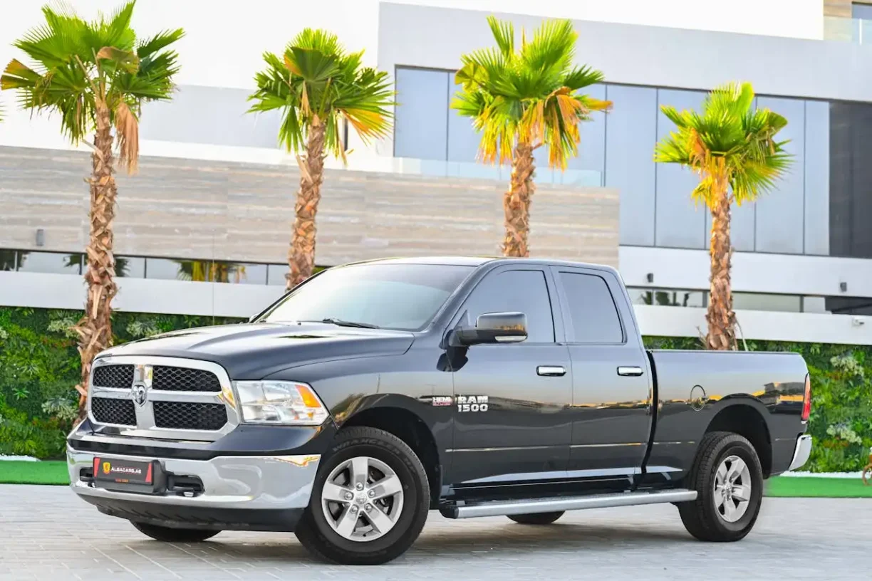 Black Dodge Ram 1500 truck parked in front of modern building with palm trees, lemonmyvehicle