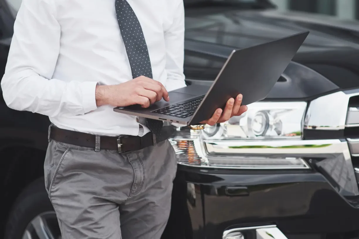 Lemon lawyer working on laptop by car for deal discussion, lemonmyvehicle