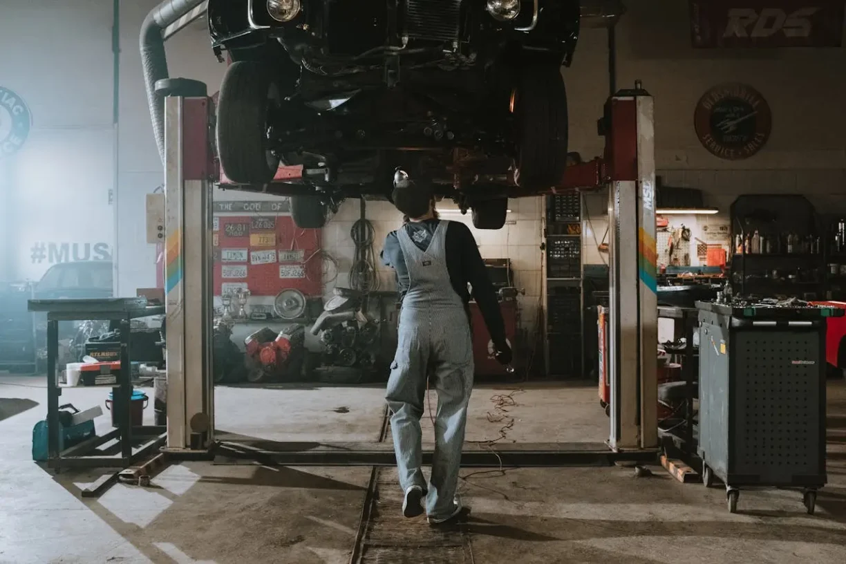 Mechanic working under car on a lift in garage workshop, lemonmyvehicle