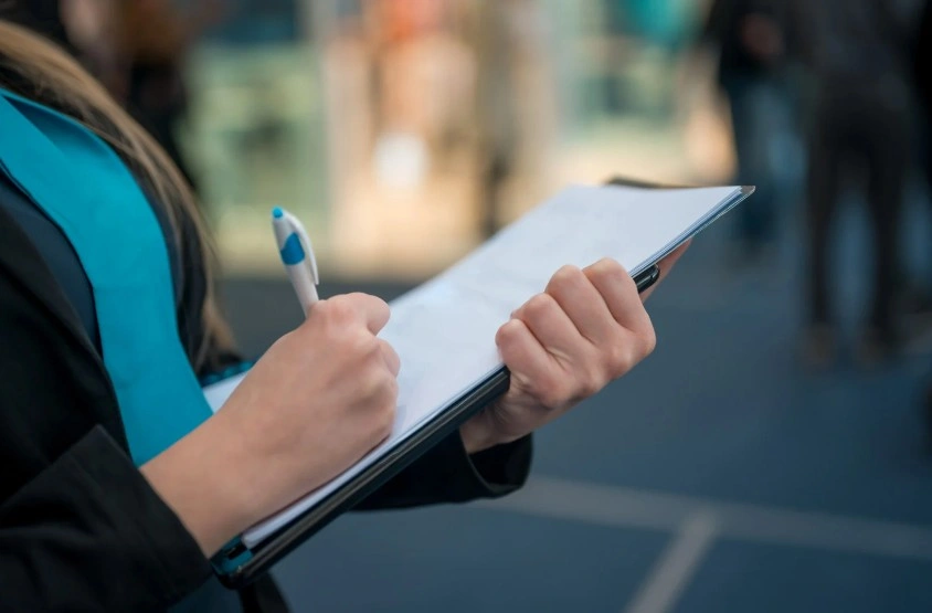 A person's hands holding a clipboard and pen, writing notes, symbolizing documentation  for a Lemon Law claim.