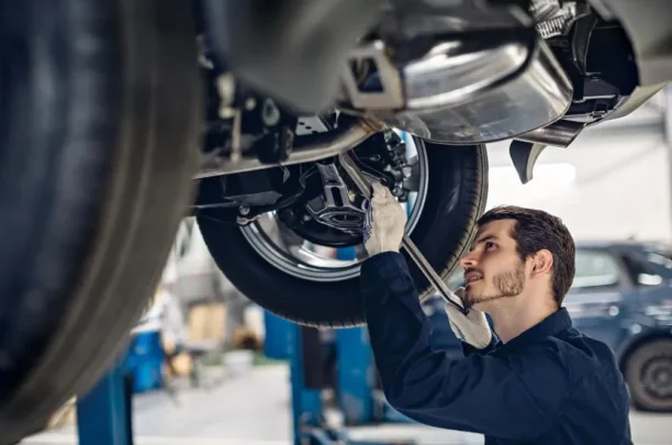 Automotive mechanic inspecting the suspension system and undercarriage of a vehicle