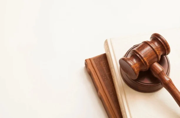 Wooden judge’s gavel placed on top of stacked legal books in a courtroom setting