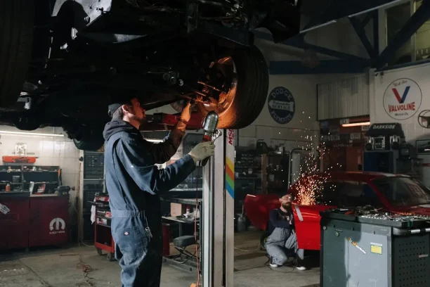 Auto mechanic repairing vehicle undercarriage with sparks flying in workshop