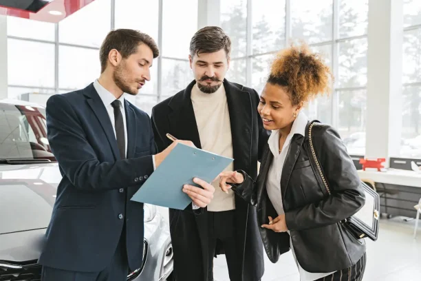 Car dealer presenting contract documents to customers at a showroom