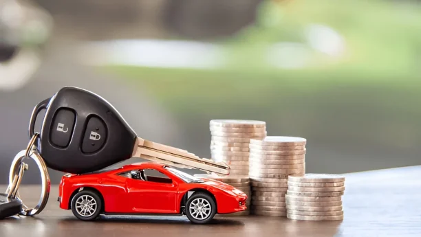 Car keys and coins beside red car model symbolizing lemon law compensation