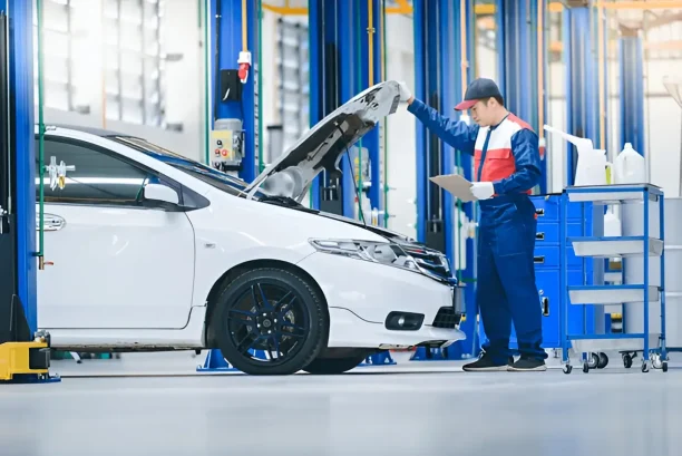 Mechanic inspecting car engine in repair shop for lemon law vehicle claim
