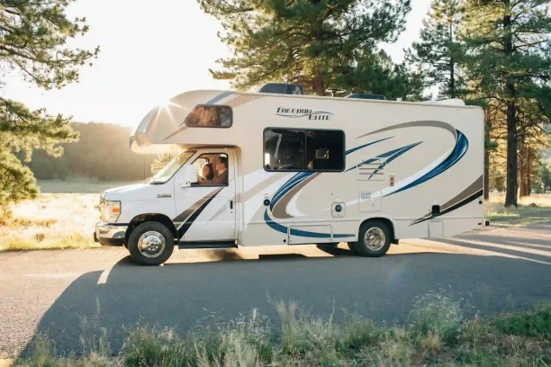 Motorhome driving through forest road at sunset representing lemon law help for defective RVs