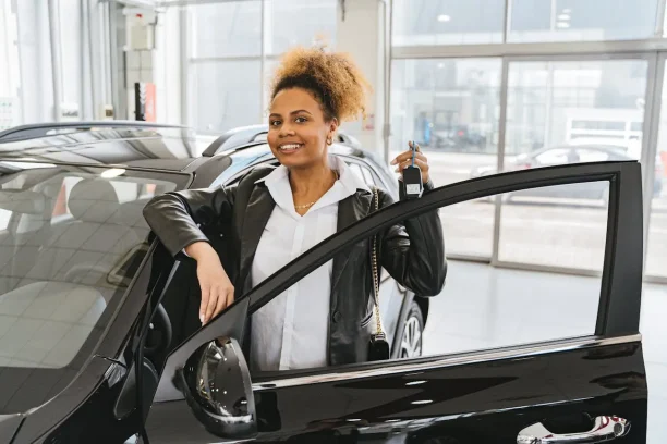 Smiling woman holding car keys at dealership after purchase under lemon law rights