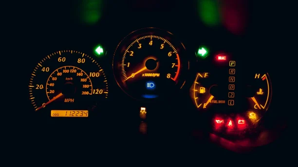Close-up of illuminated car dashboard showing speedometer and warning lights