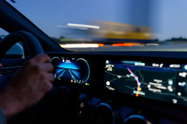 Driver steering at night with digital speedometer and navigation display