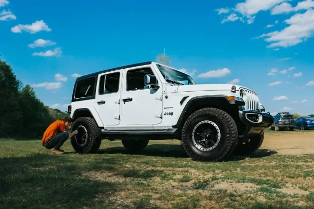 White Jeep SUV being checked by a man outdoors on a sunny day.