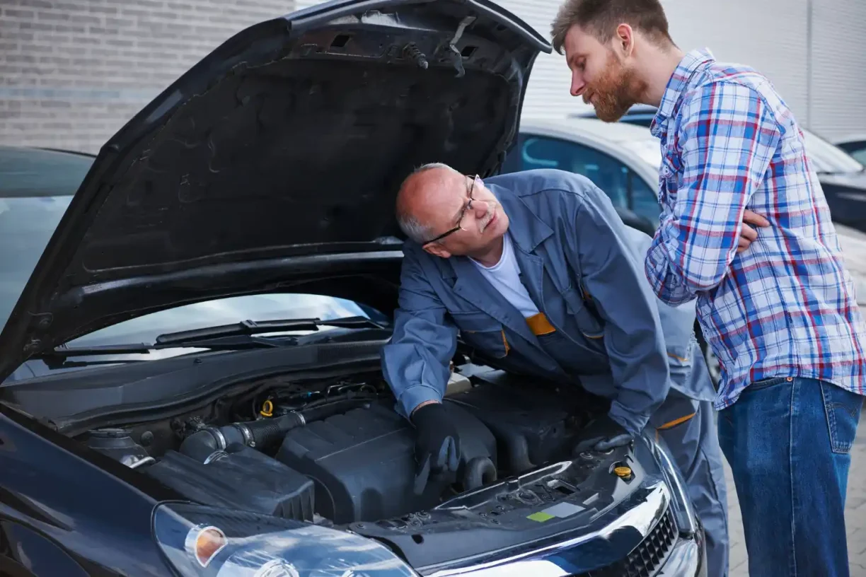 Car owner consulting a mechanic about repeated engine problems that may qualify for a Lemon Law case