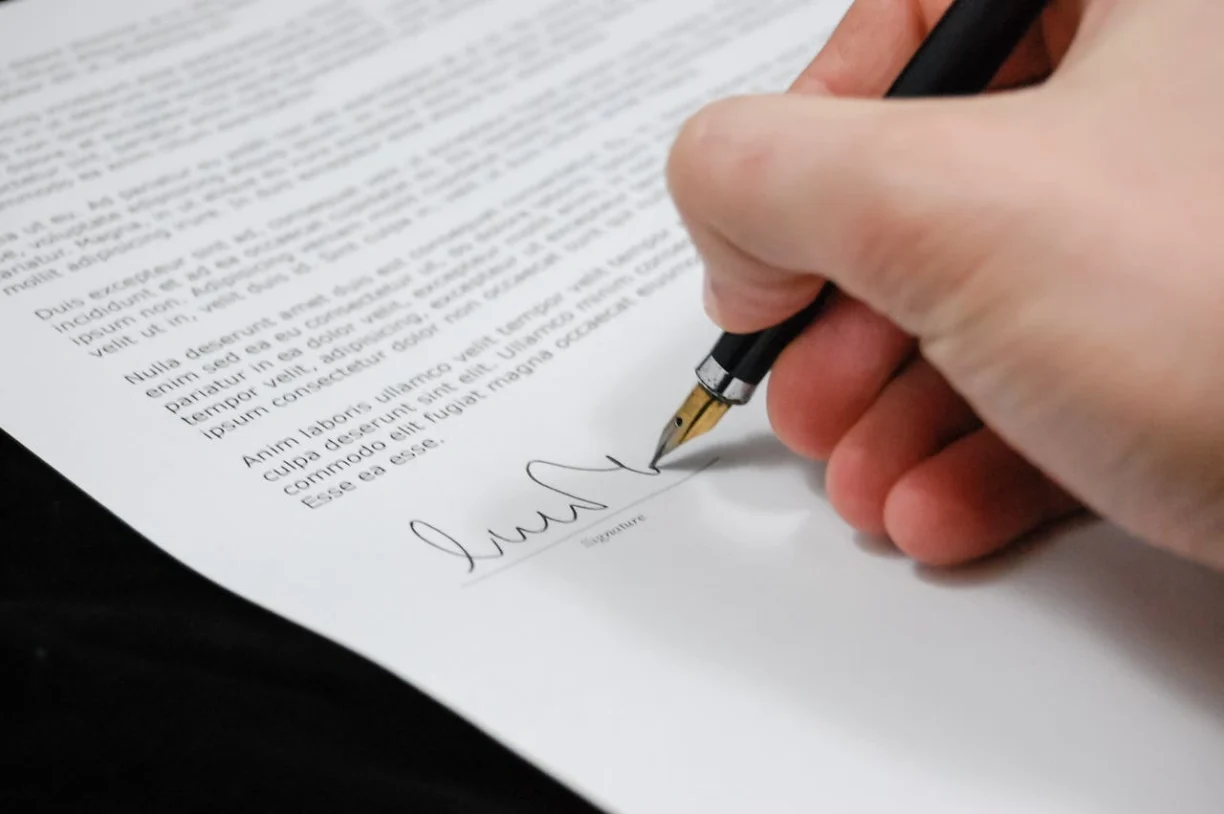 Close-up of a person signing a legal document with a fountain pen