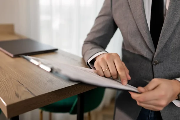 Close-up of a professional reviewing and signing official documents at a desk, representing legal paperwork, claims processing, or vehicle dispute documentation.