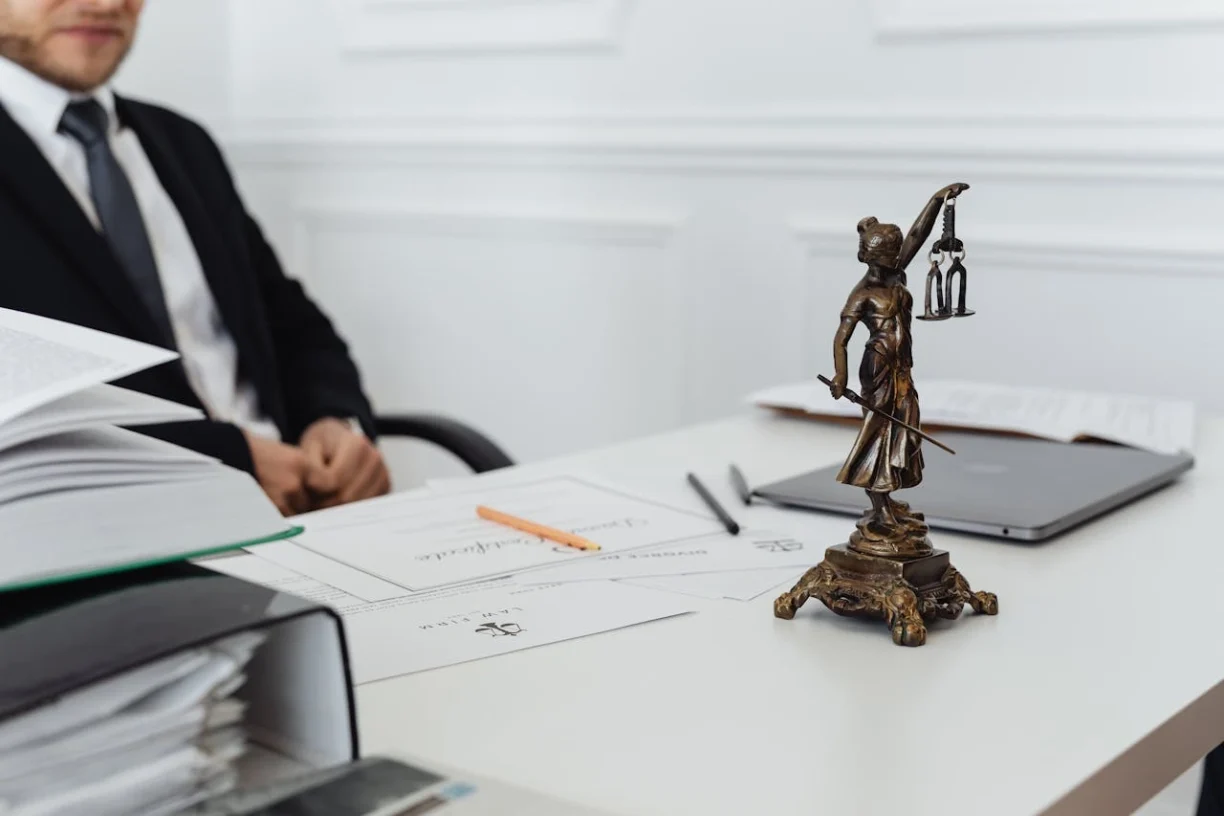 Lady Justice statue placed on a desk with legal documents and files, representing consumer rights, legal review, and professional legal consultation.