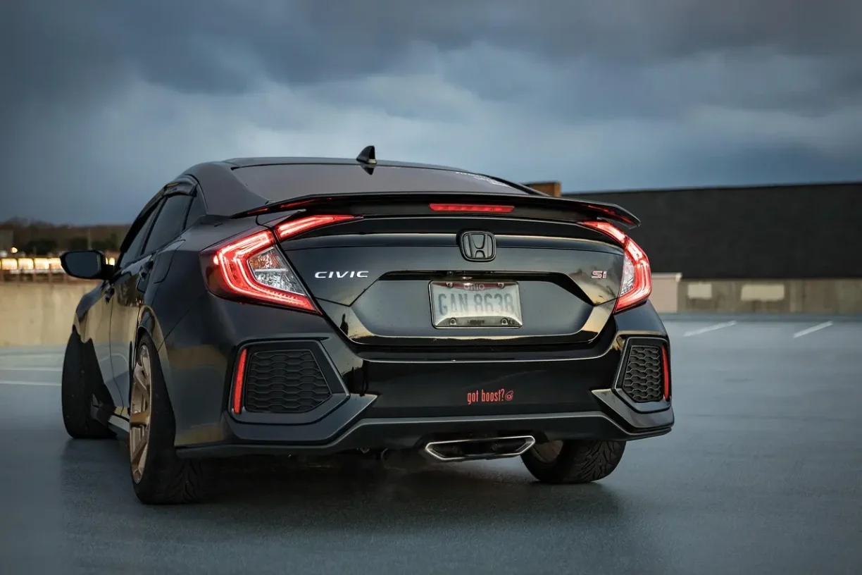 Rear view of a black Honda Civic Si parked outdoors with illuminated taillights