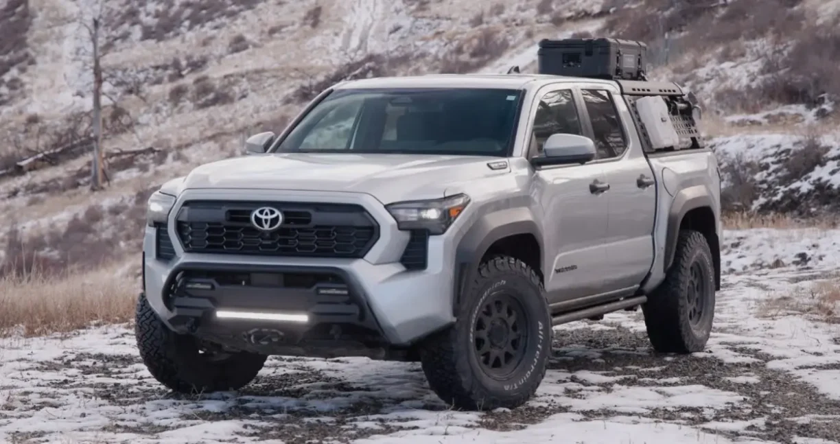 Rugged Toyota Tacoma pickup equipped for off road driving in a snowy mountain landscape.