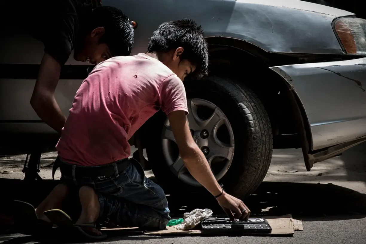 Two individuals performing roadside repairs on a vehicle, illustrating the mechanical reliability issues and safety concerns that led to the Ford CP4 recall.